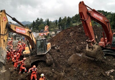 Petugas penyelamat dengan dibantu alat berat berusaha menemukan para korban yang terkubur tanah longsor di desa Shuicheng di Guizhou, Selasa (23/7/2019).