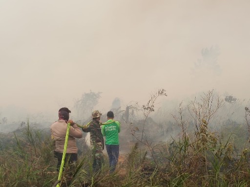 Tampak tim memadamkan api di lokasi lahan terbakar.