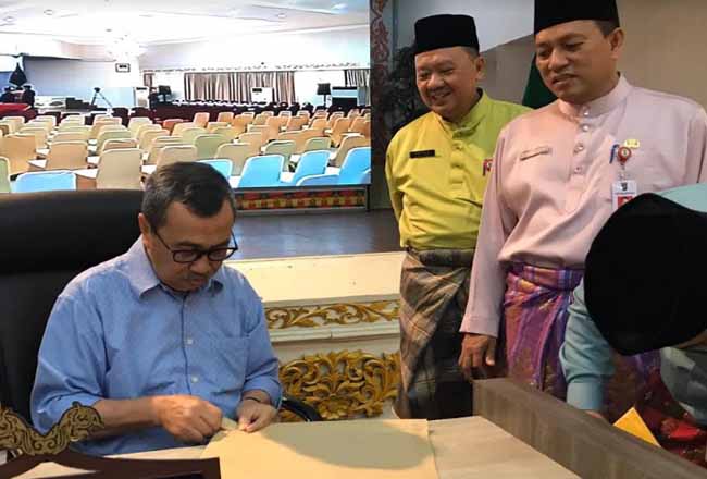 Gubernur Riau Syamsuar saat membuka berkas yang masih bersegel. Foto: Riauterkini