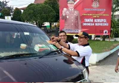 Kejari Inhu Supardi SH didampingi Kasi Intel Jaksa Inhu Bambang Dwi Syahputra SH MH memberikan stiker anti korupsi kepada para pengguna jalan.