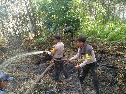 Petugas Polisi Polsek Tebingtinggi sedang memadamkan api di Desa Lukun.