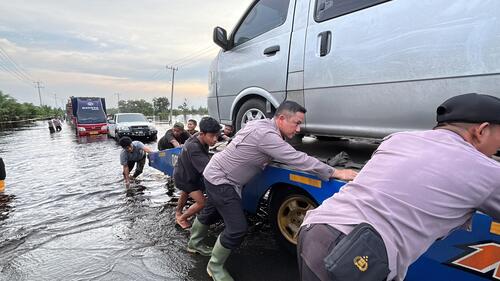 Kapolres Pelalawan, AKBP Afrizal Asri bersama personel Polres Pelalawan turun tangan membantu evakuasi kendaraan yang terjebak banjir