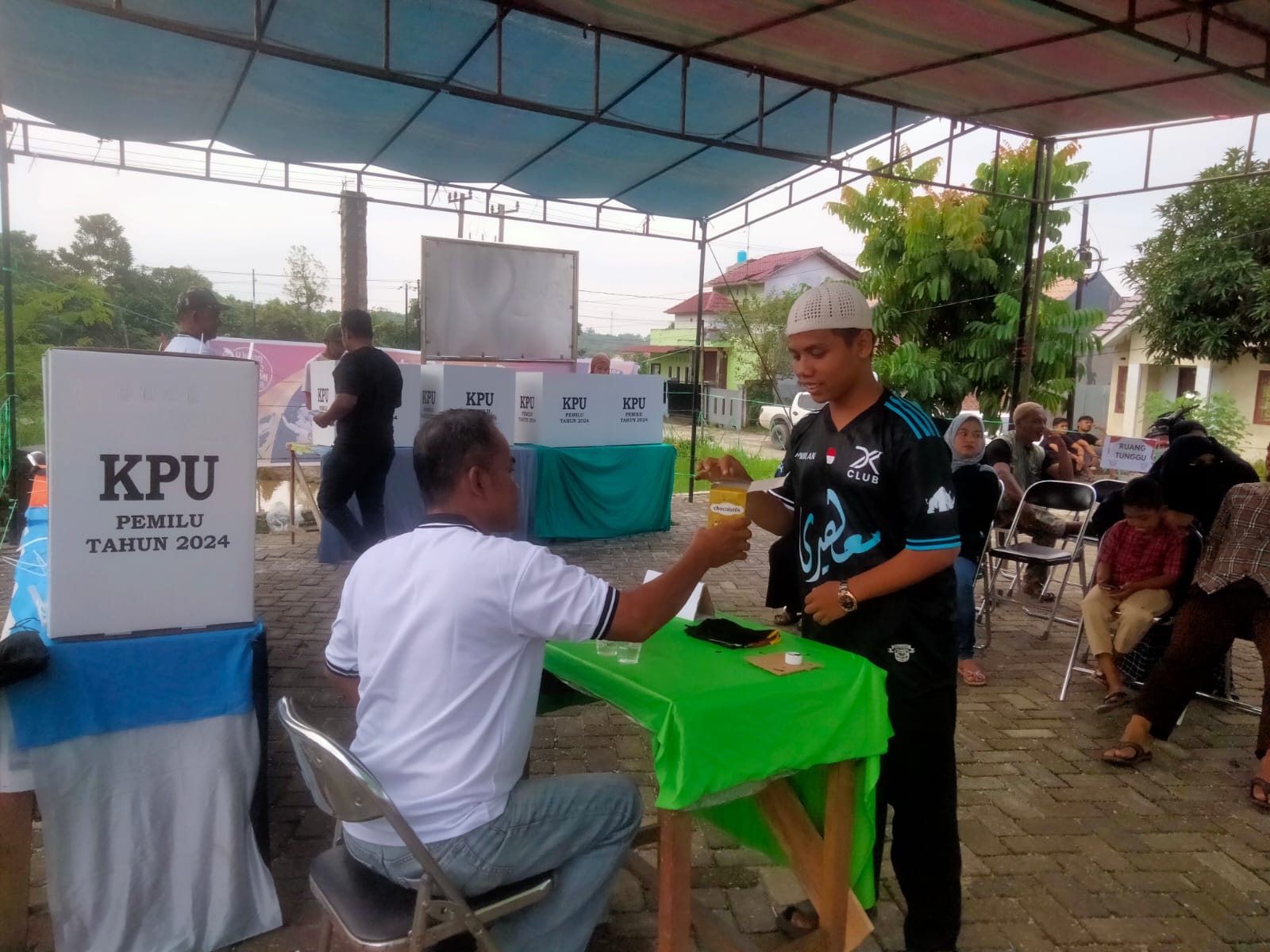 Petugas TPS 01 Sialang Rampai Kulim berikan cokelat bagi pemilih yang sudah nyoblos (foto:Rinai/halloriau)