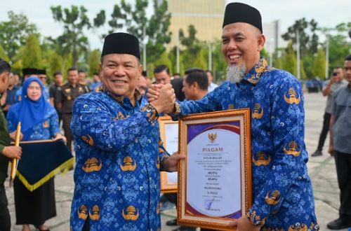 Walikota Dumai, Paisal menerima penghargaan UHC yang diserahkan Plt Gubernur Riau, SF Hariyanto saat peringatan HKN ke-61.(foto: bambang/halloriau.com)