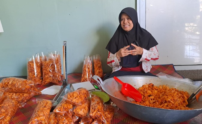 Yukhonis atau Bu Onis sedang membungkus keripik singkong Aira pedas dan gurih (foto/riki)