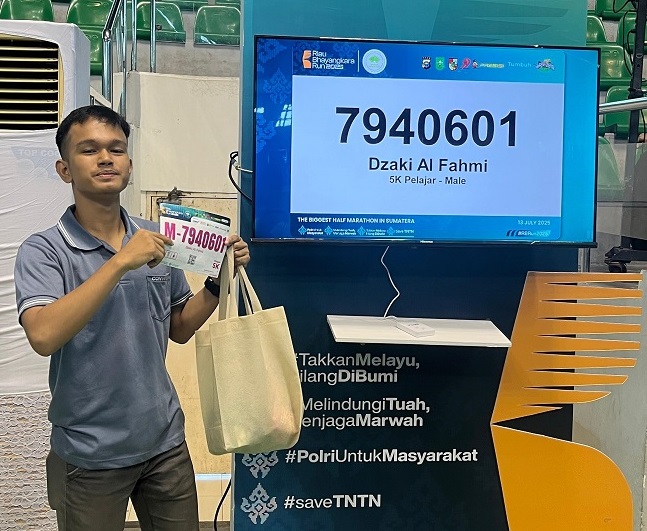 Fahmi, salah seorang peserta Riau Bhayangkara Run 2025, memperlihatkan nomor peserta saat proses BIB Checking di Pekanbaru, Jumat (11/7/2025).