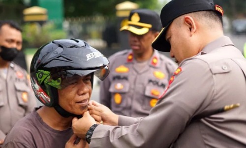 Kapolresta Pekanbaru, Kombes Pol Pria Budi memasangkan helm kepada pengendara saat Operasi Lancang Kuning 2023.(foto: mcr)