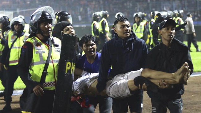 Seorang Aremania pingsan dibopong saat tragedi Kanjuruhan.(foto: cnnindonesia.com)