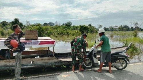 Warga Langgam memanfaatkan kapal kayu untuk penyeberangan akibat banjir.(foto: tribunpekanbaru.com) 