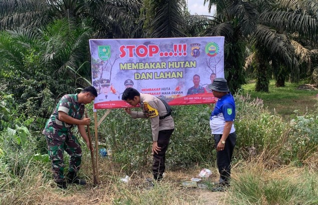 Kades Tuah Pelang bersama Babinsa dan Bhabinkamtibmas pasang spanduk imbauan larangan membakar lahan dan hutan (foto/diana)