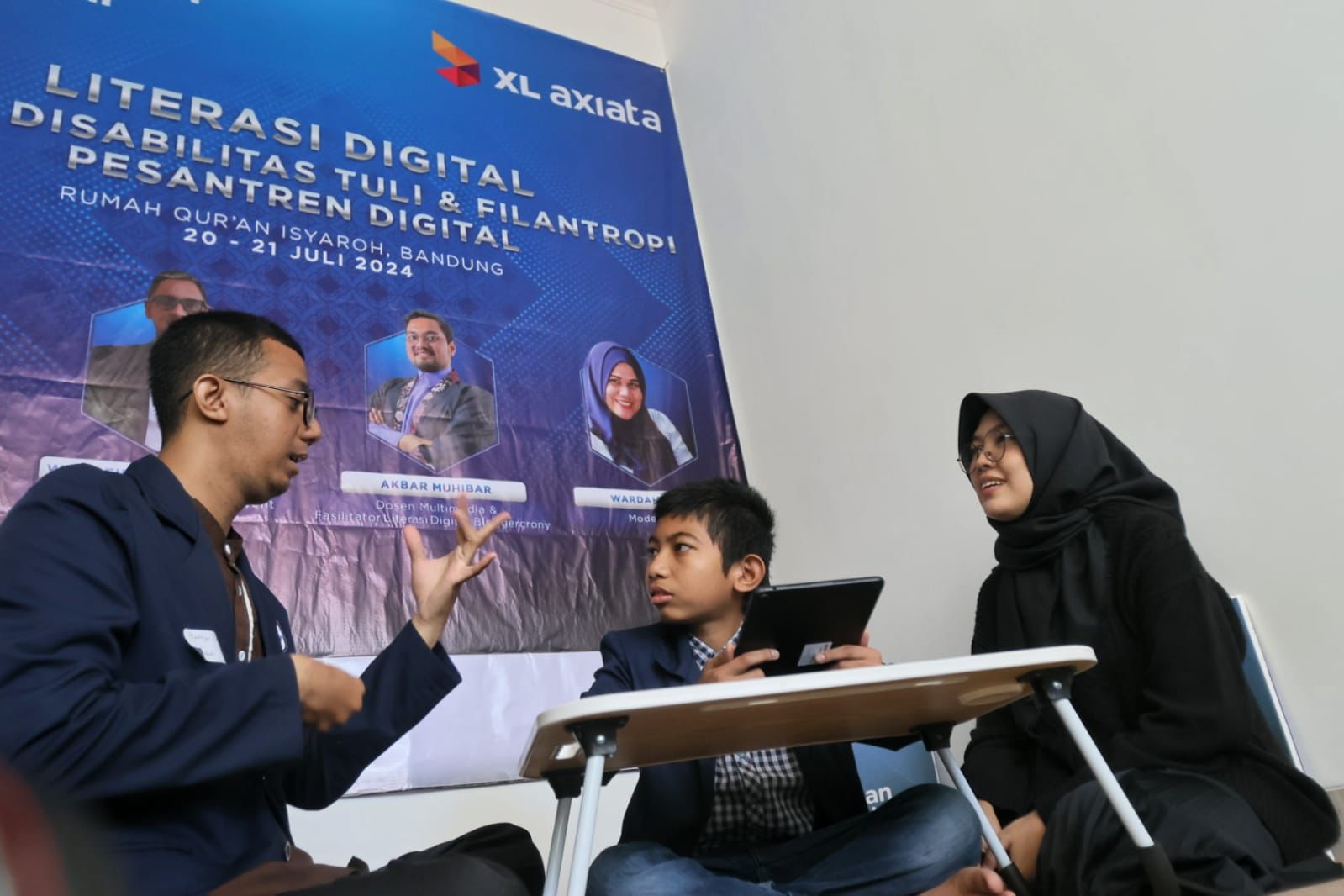 Juru Bahasa Isyarat (kanan), sedang menjurubahasakan kegiatan yang sedang berlangsung kepada dua santri disabilitas tuli dari Rumah Qur’an Isyaroh di Bandung.(foto: istimewa)