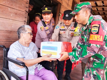 Kapolsek Kuala Kampar AKP Rhino Handoyo, Bhabinkamibmas Eko A dan Bripda Dedi saat memberikan bingkisan pada Jima, warga Dusun 2 Desa Tanjung Selukup.(foto: andi/halloriau.com)