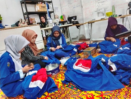 Para karyawan RJL dan anak magang yang tengah merapihkan jahitan logo perusahaan yang sudah terpasang.(foto: andi/halloriau.com)