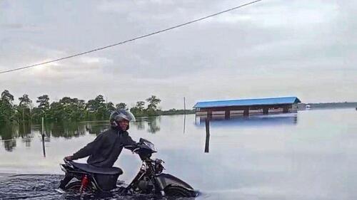 Seorang warga mendorong sepeda motornya yang mogok menerobos banjir di Jalintim Kilometer 83. (Foto: Tribun Pekanbaru)