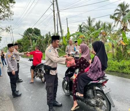 Kapolsek Tembilahan Hulu, IPTU Hasan Basri, didampingi sejumlah personel Polsek Tembilahan Hulu memberikan takjil ke masyarakat (Foto: Ayendra)