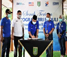 Plh Walikota Dumai, Herdi Salioso menandatangani berita acara serah terima program CSR dari Bank BRI Dumai, Rabu (23/12/2020). Foto Bambang