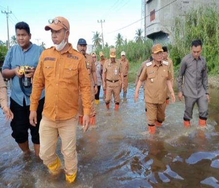 Bupati Rohil Bistamam, didampingi Wabup Jhony Charles, meninjau ruas jalan dan pemukiman warga yang terdampak banjir di Bagansiapiapi. (Foto: Afrizal)