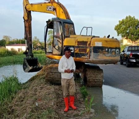 Kepala Dinas LH Rohil, Suwandi melakukan normalisasi parit (foto/afrizal)