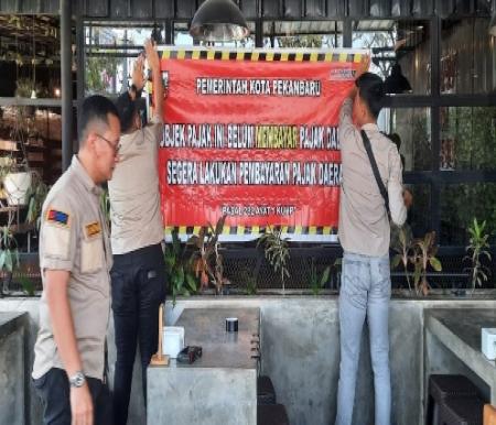 Spanduk ditempel Bapenda Pekanbaru di objek pajak di dua lokasi yang berbeda (foto/rahmat)