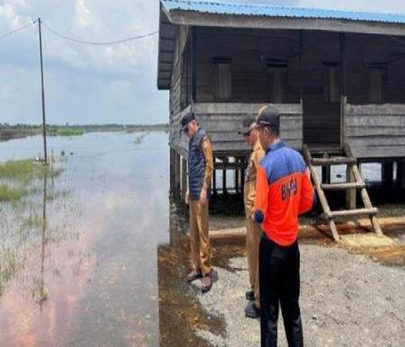 Personel BPBD Pelalawan memantau kondisi banjir di sekitar Jalan Lintas Timur (Jalintim) Kilometer 83. (Foto: Tribun Pekanbaru)