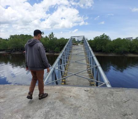 Seorang pegawai PUPR terlihat sedang melihat jembatan Selat Akar ambruk